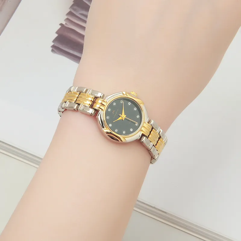 Vintage women's gold two-tone quartz watch worn on wrist, featuring a black dial and rhinestone accents.