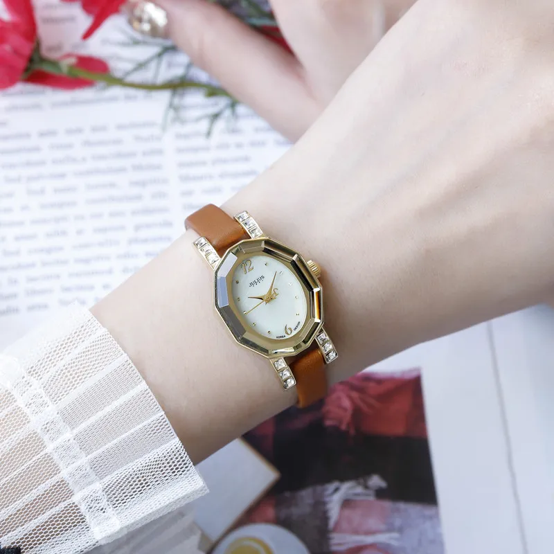 Vintage women’s watch with gold-tone case, leather strap, and shell dial with crystal details