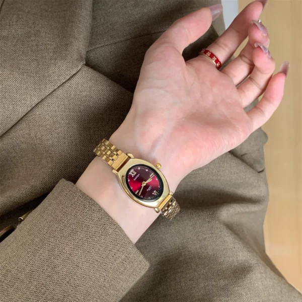 Vintage gold oval women’s watch with red dial on wrist