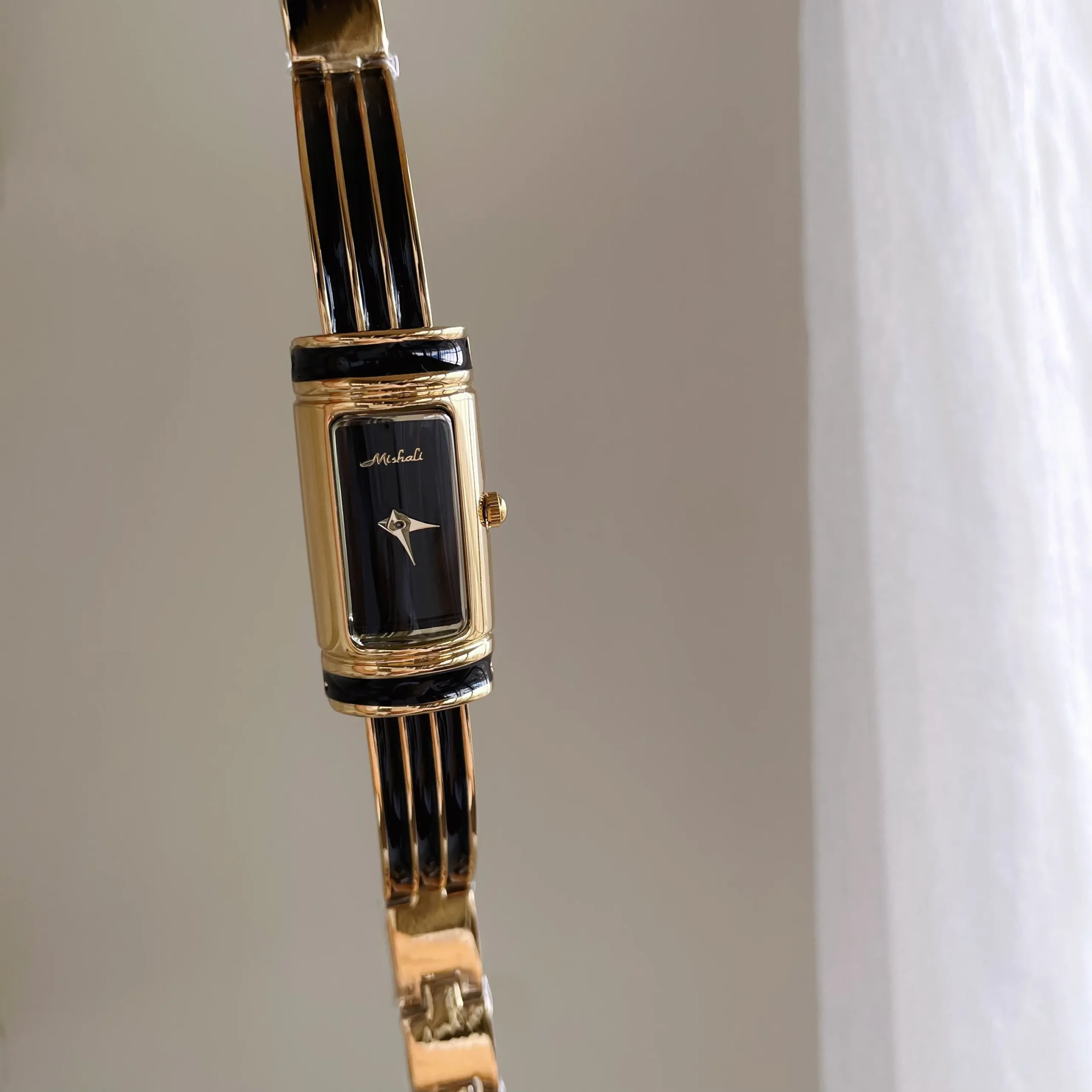 Vintage gold rectangular women’s bracelet watch with black dial and gold case – retro slim bar design.