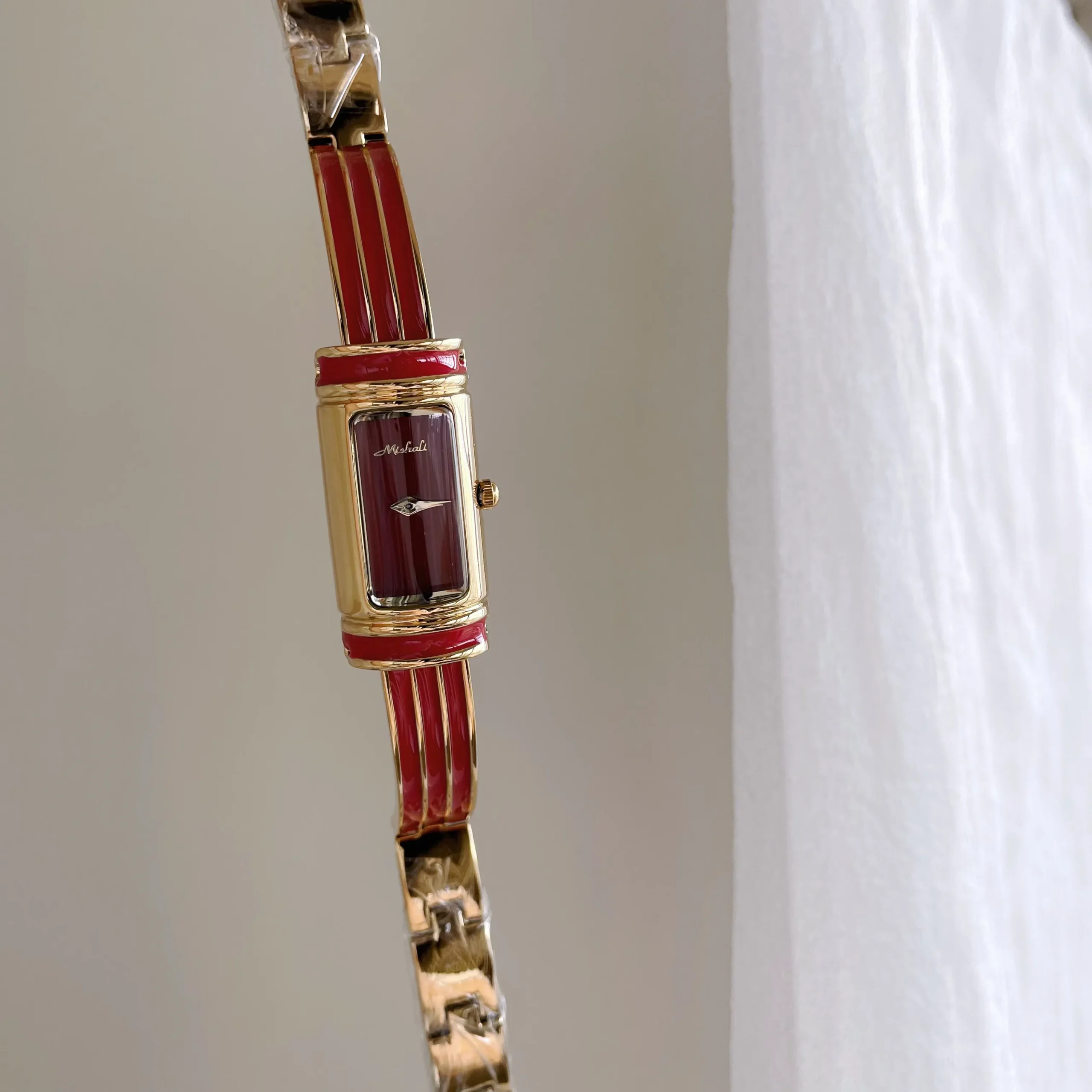Vintage gold rectangular women’s bracelet watch with red dial and gold case – bold retro slim bar design.