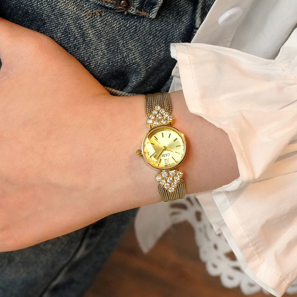 Vintage gold women’s watch with champagne dial on wrist, crystal accents and woven strap – WatchTrio