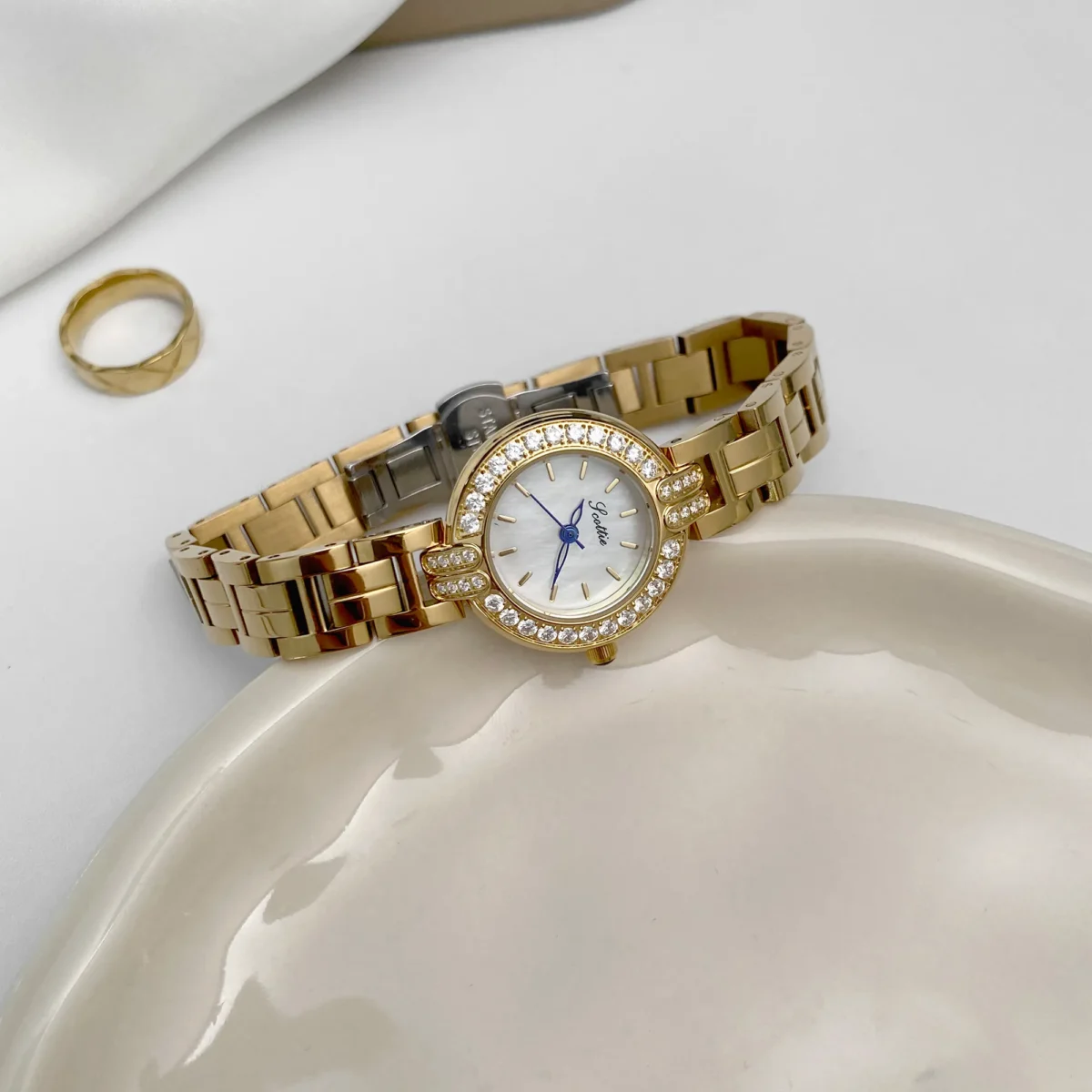 Vintage gold women’s watch with round crystal bezel and white dial on display – WatchTrio