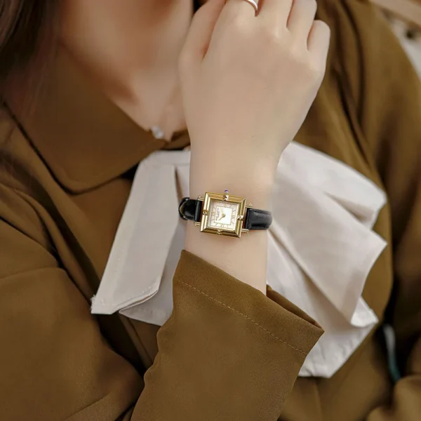 Vintage leather ladies watch with gold square case and black strap on wrist – WatchTrio