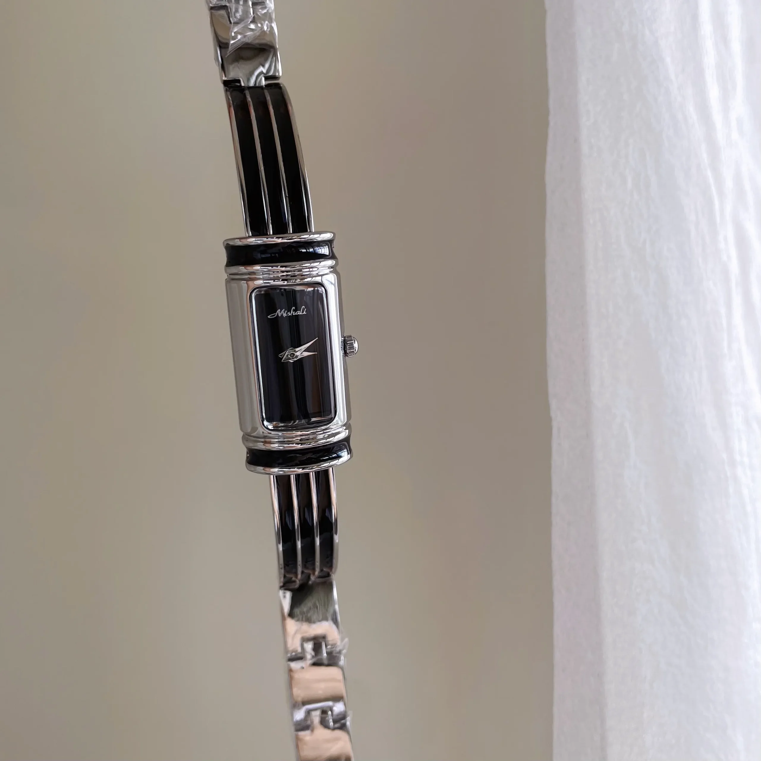 Vintage silver rectangular women’s bracelet watch with black dial and silver case – classic retro slim bar design.
