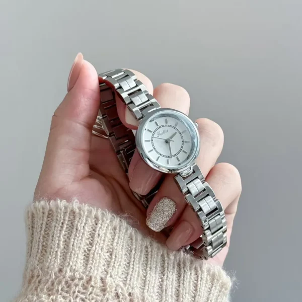 Vintage silver round women’s watch with white dial held in hand, 26mm stainless steel bracelet