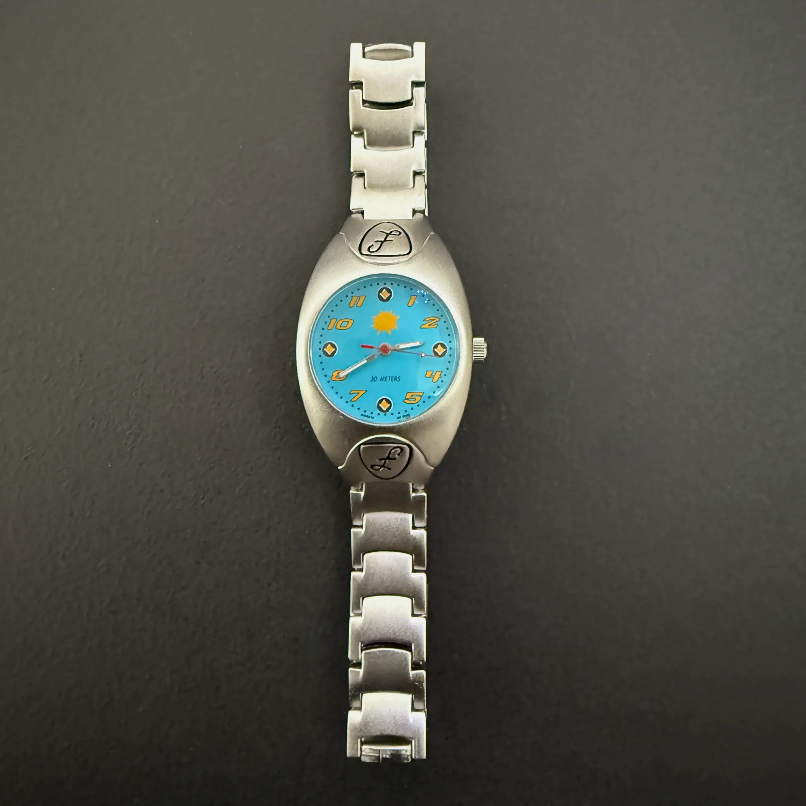 Vintage silver women’s quartz watch with blue dial and sunburst spark design