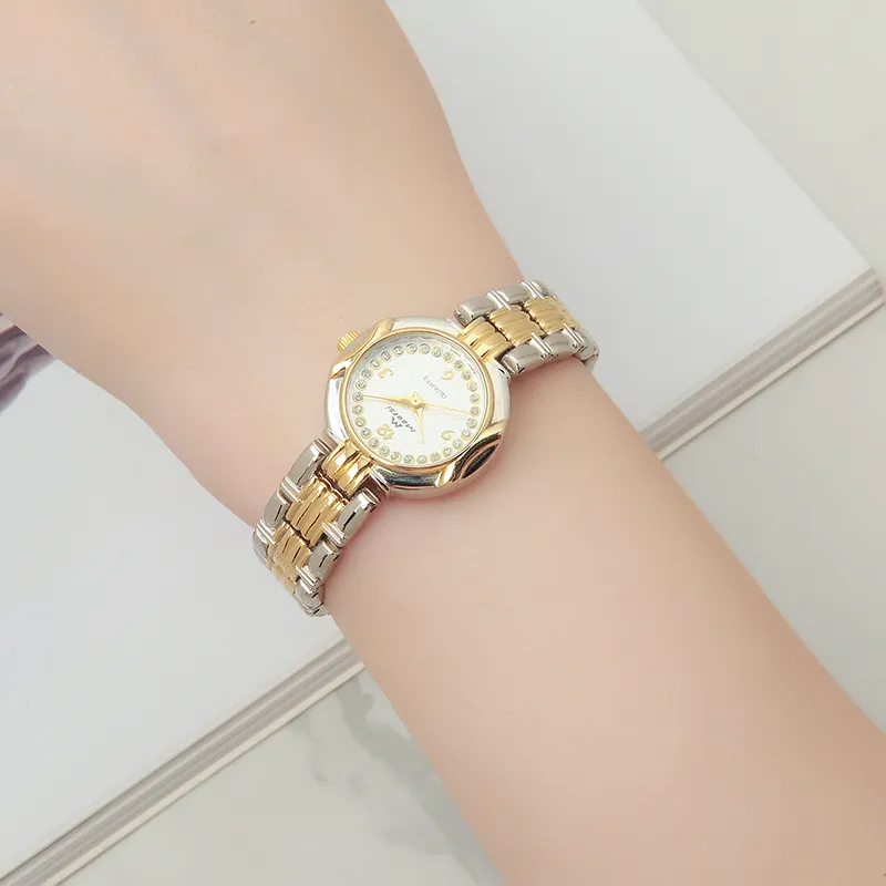 Wrist shot of a vintage women's gold quartz watch with a white dial and traditional Arabic numeral markings.