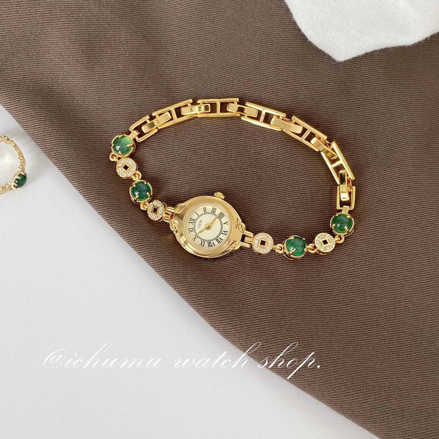 Flatlay of WatchTrio vintage gold bracelet women’s watch with jade accents on brown fabric
